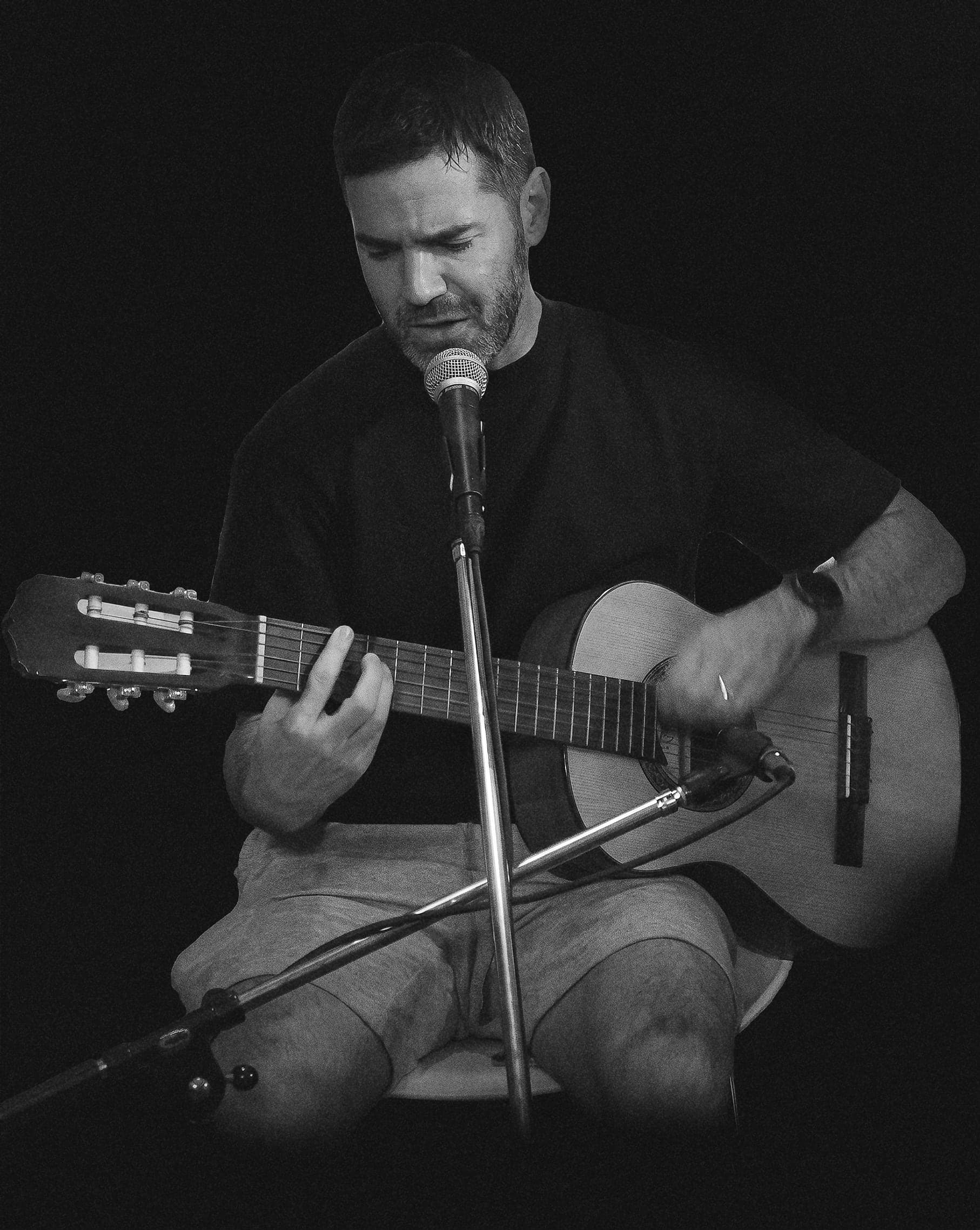 En vivo: sentado, tocando la guitarra criolla frente al micrófono